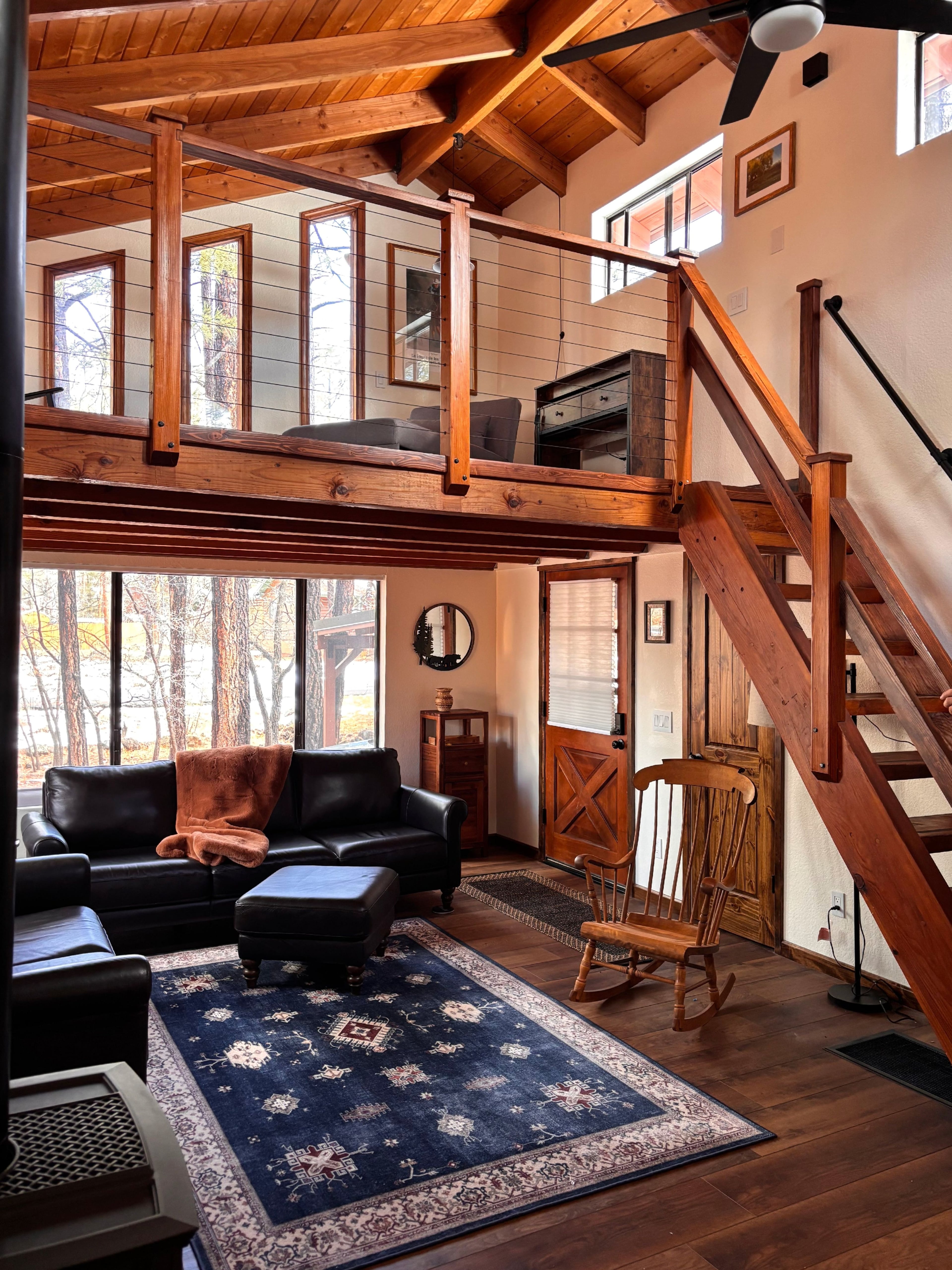 Great room with loft, leather seating, and pine views